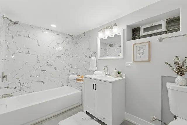 a bathroom with a bathtub sink mirror and toilet
