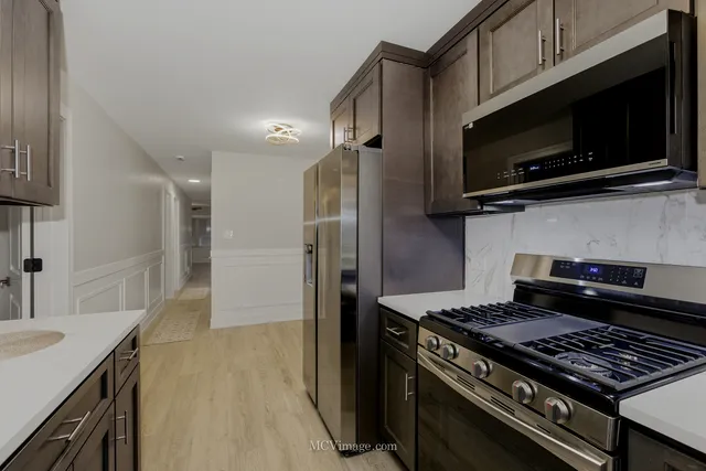 a kitchen with stainless steel appliances a sink a stove and cabinets