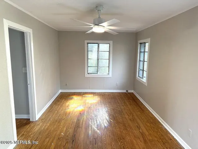 a view of an empty room with wooden floor and a window
