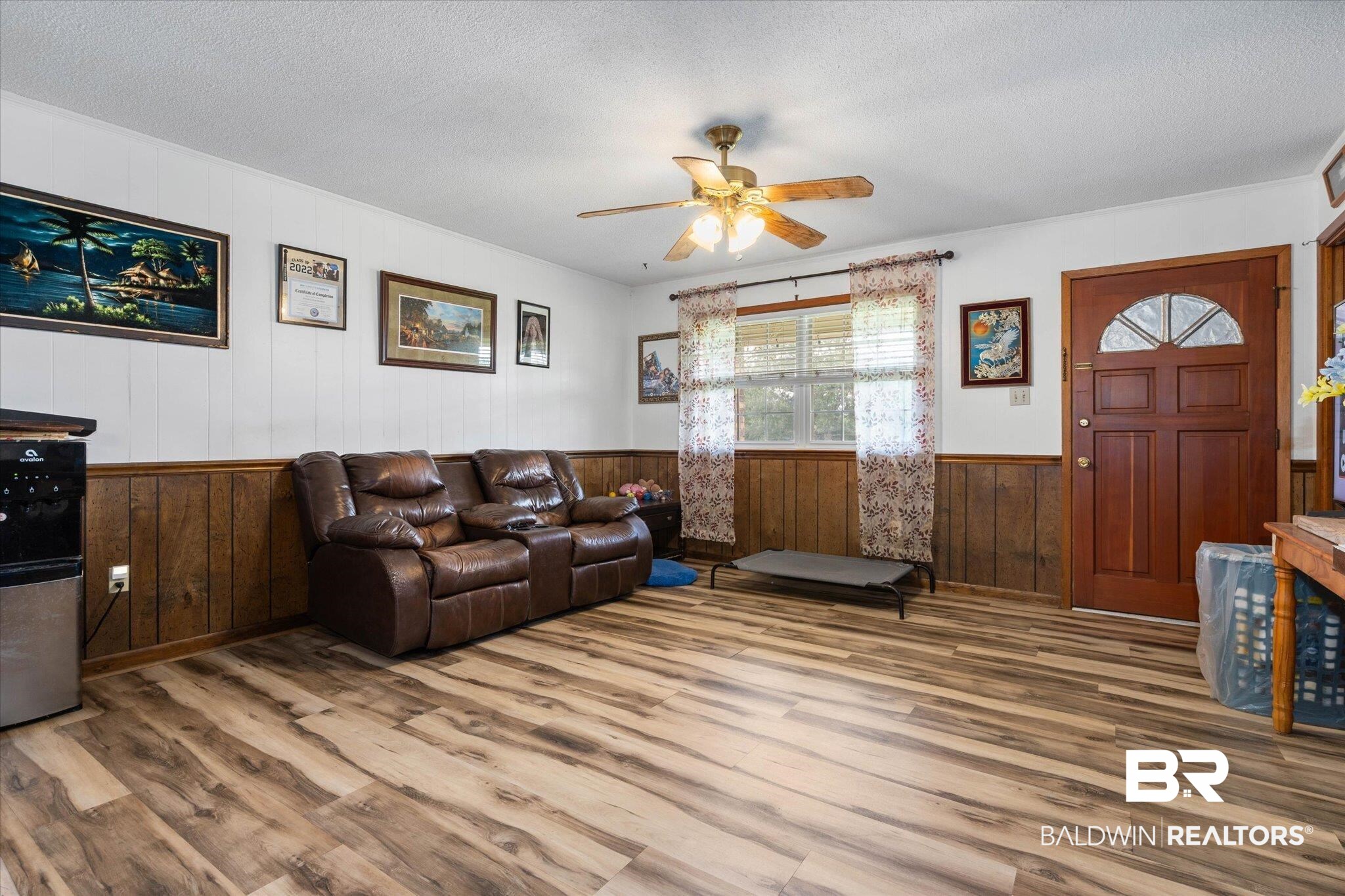 11601 Lott Road Chunchula, AL 36521 - Photo 4 of 34 Living room with wood finished floors, a ceiling fan, wood walls, wainscoting, and a textured ceiling