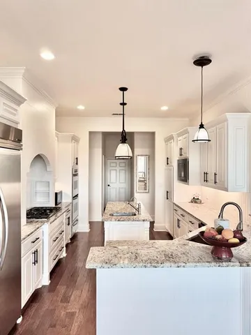 a large kitchen with granite countertop a stove a sink a refrigerator and a wooden floor