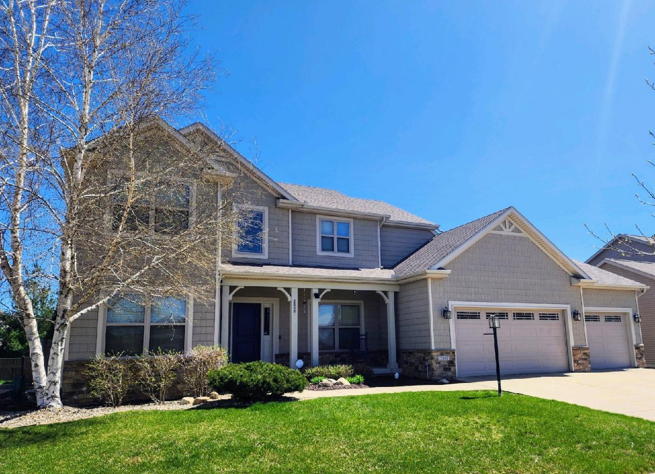 a view of a yard in front of a brick house with plants and large tree