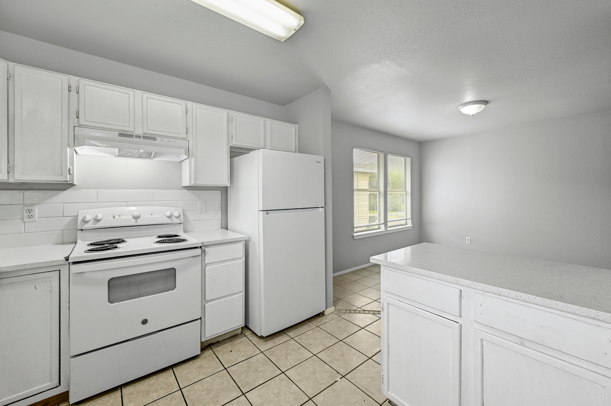 2212 Katy Lane Georgetown, TX 78626 - Photo 14 of 27 The kitchen features white cabinetry, white appliances, and a tiled backsplash