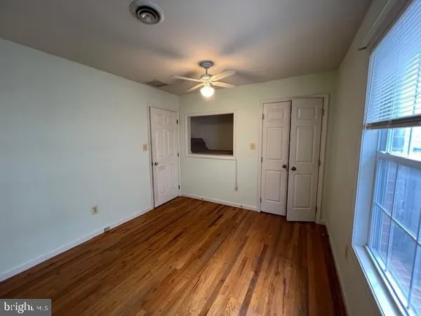 a view of empty room with wooden floor and fan