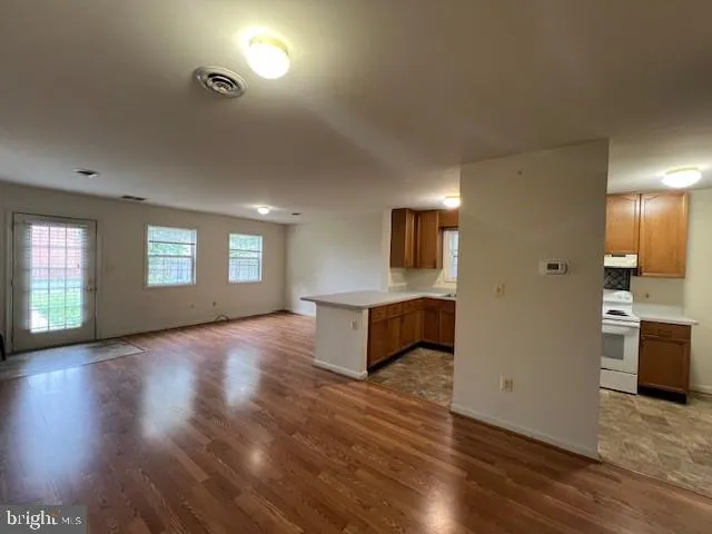 a view of an empty room with window and wooden floor