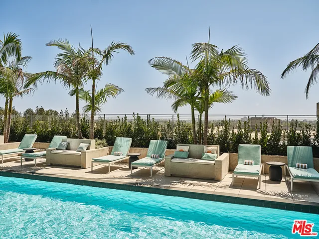 a view of a swimming pool with couches and lounge chairs