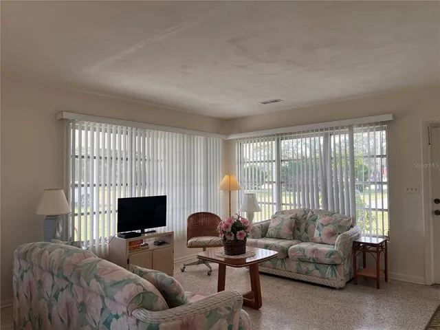 a living room with furniture a flat screen tv and a large window