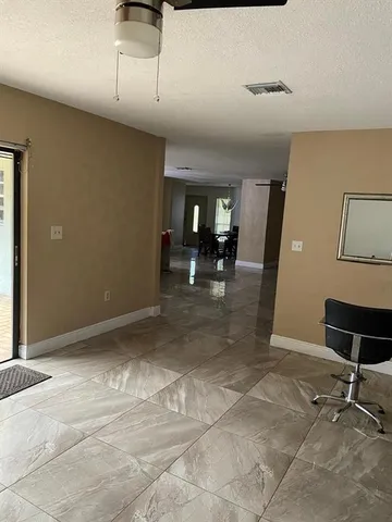 a view of a refrigerator in kitchen and an empty room