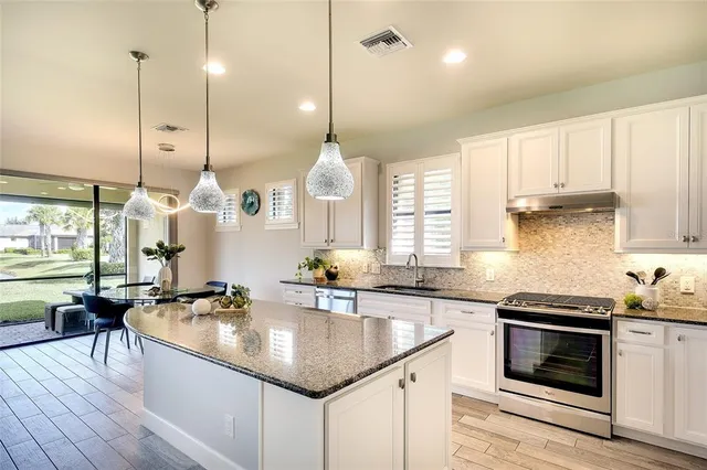 a kitchen with stainless steel appliances granite countertop a sink a stove and a wooden floors