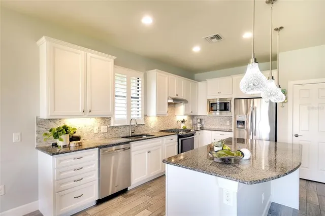 a kitchen with stainless steel appliances granite countertop a sink a stove and a granite counter tops