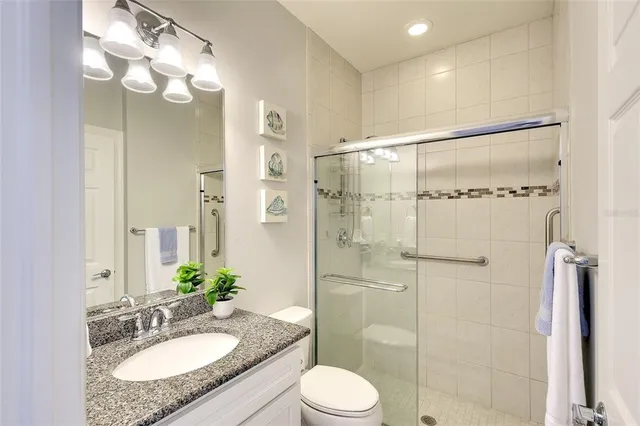 a bathroom with a granite countertop sink toilet mirror and shower