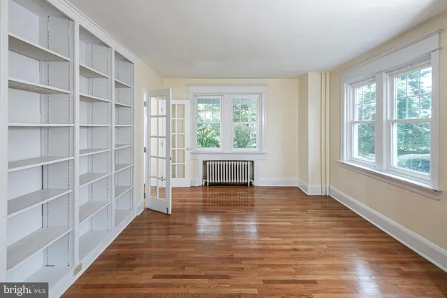 a view of an empty room with a window and wooden floor