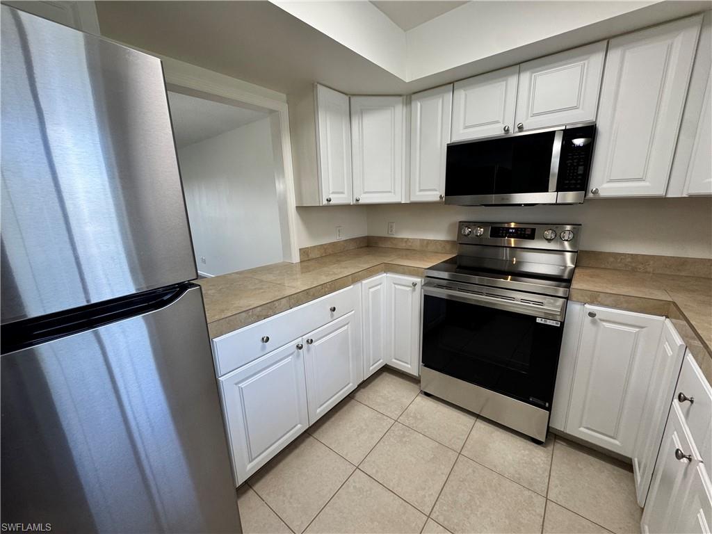5667 Rattlesnake Hamm Road North, Unit B301 Naples, FL 34113 - Photo 5 of 17 a kitchen with white cabinets and black appliances
