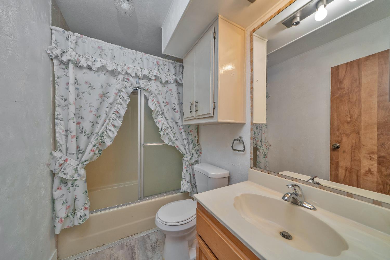 4420 Pleasant Valley Road, Unit 116 Diamond Springs, CA 95619 - Photo 22 of 28 a bathroom with a sink a toilet and shower curtain