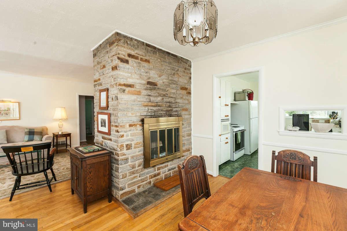 1331 Heather Hill Road Baltimore, MD 21239 - Photo 7 of 28 a living room with furniture a fireplace and a dining table with wooden floor