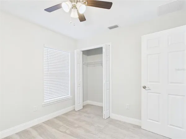 an empty room with windows and fan