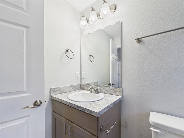 a bathroom with a granite countertop sink a toilet and a mirror