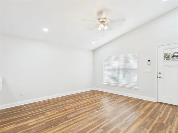 an empty room with wooden floor and windows