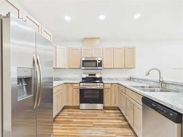 a kitchen with stainless steel appliances granite countertop a sink and a refrigerator