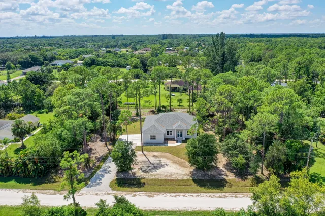 an aerial view of a house with a yard and large trees