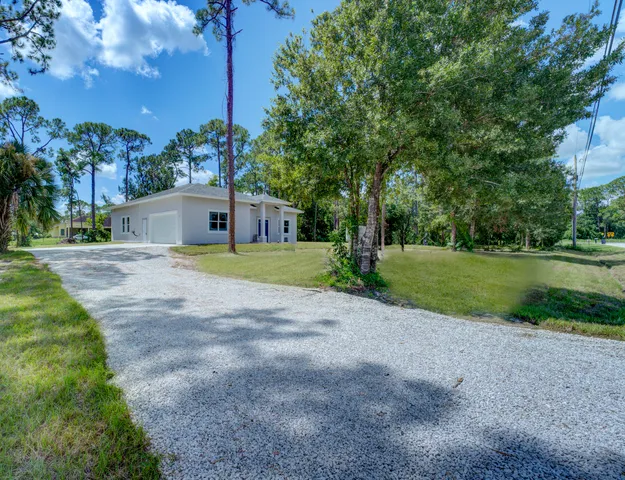 a view of a house with a big yard and large trees