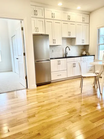 a kitchen with stainless steel appliances granite countertop a refrigerator a stove and white cabinets