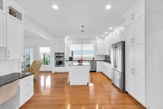 a large white kitchen with lots of counter space wooden floor and appliances