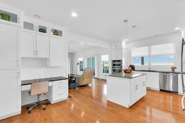 a kitchen with stainless steel appliances a stove top oven a sink a refrigerator white cabinets and wooden floor