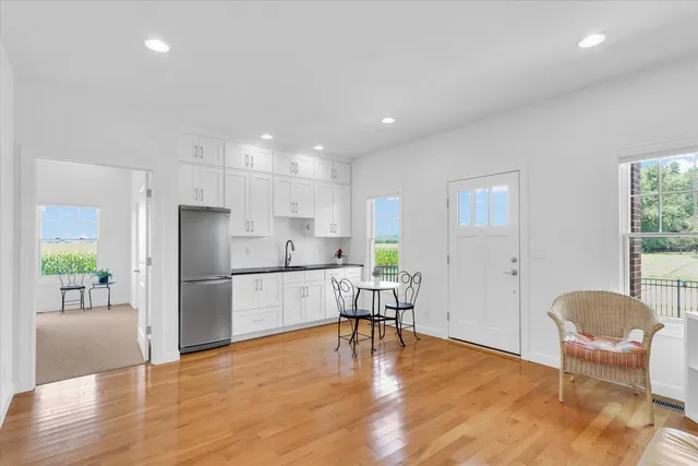 a kitchen with stainless steel appliances granite countertop a refrigerator a stove a dining table and chairs with wooden floor