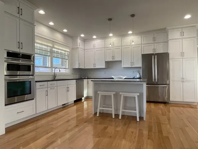 a kitchen with kitchen island granite countertop a sink cabinets and stainless steel appliances