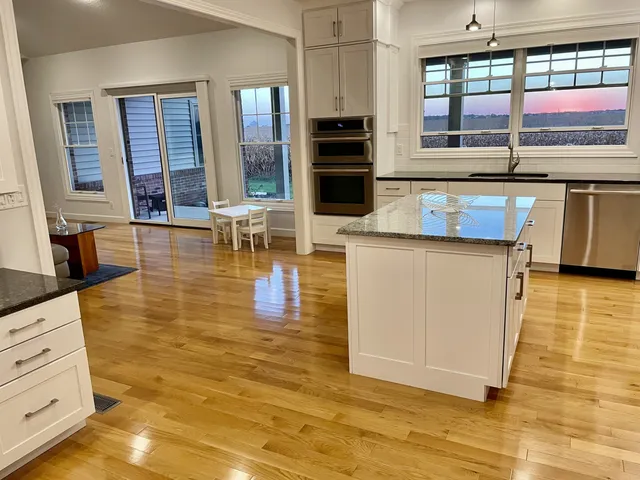 a living room with stainless steel appliances kitchen island granite countertop a stove and a wooden cabinets