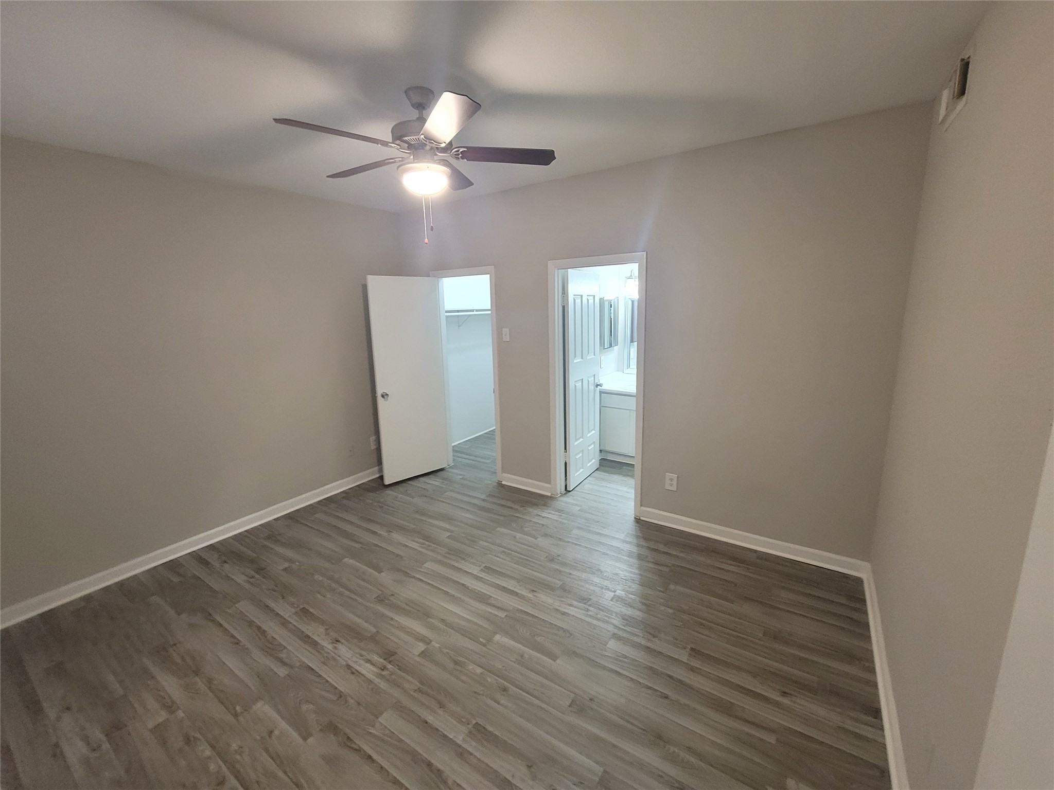 7250 West Greens Road, Unit 108 Houston, TX 77064 - Photo 3 of 9 a view of an empty room with wooden floor and a fan