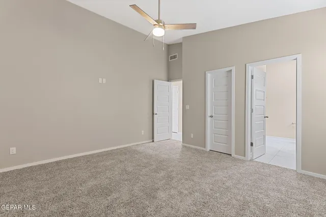 an empty room with closet and a ceiling fan