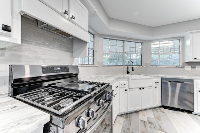 a kitchen with a stove a sink and wooden floor