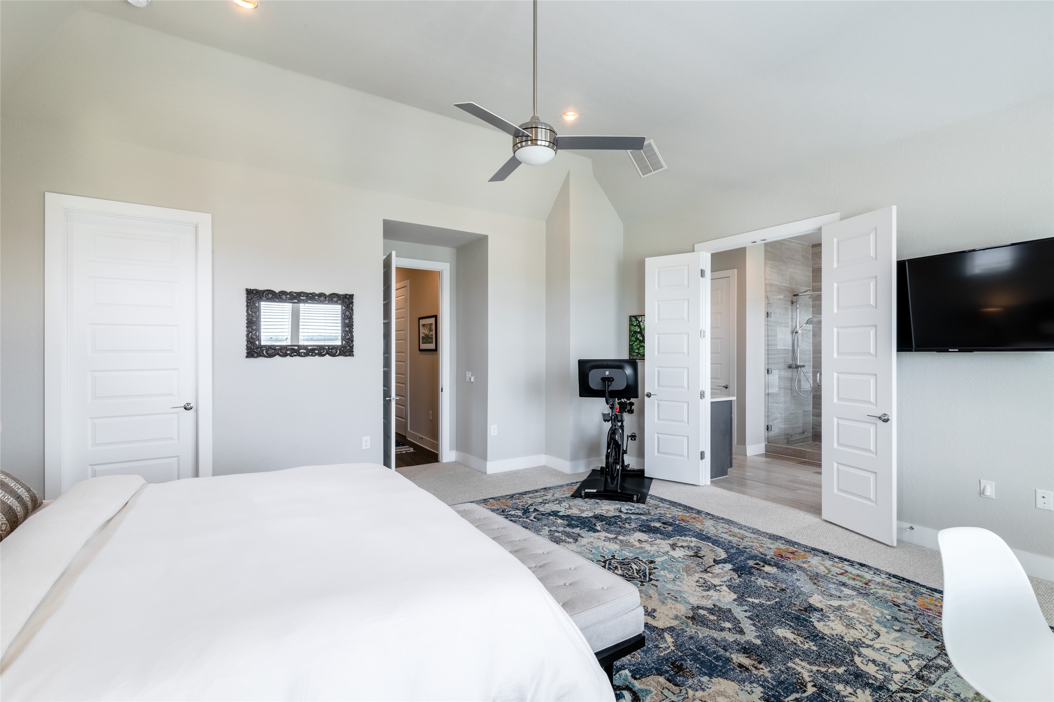 6025 Seville Drive Austin, TX 78724 - Photo 14 of 40 Spacious primary bedroom featuring high ceiling with a ceiling fan, recessed lighting, and soft gray carpeting with view to the primary bathroom