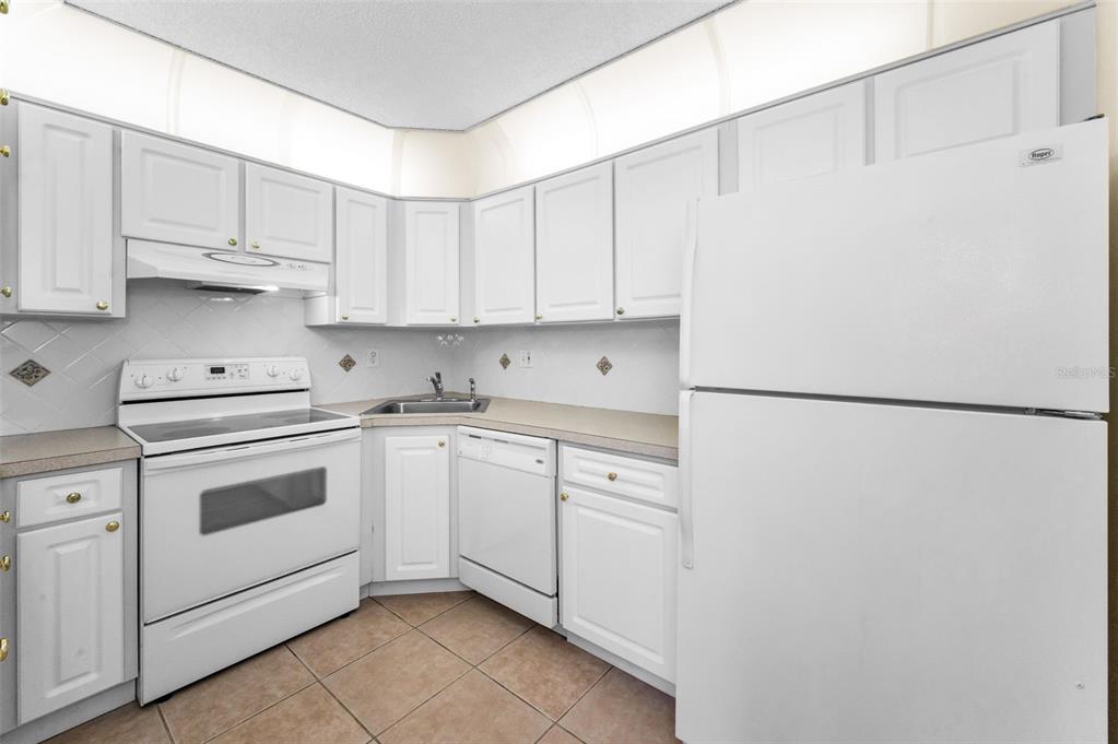 2687 Pine Ridge Way South, Unit F2 Palm Harbor, FL 34684 - Photo 26 of 62 a kitchen with white cabinets and white appliances