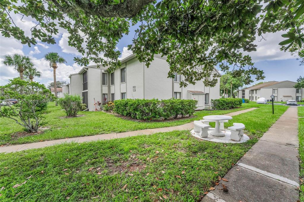 2687 Pine Ridge Way South, Unit F2 Palm Harbor, FL 34684 - Photo 37 of 62 a front view of a house with a yard and potted plants