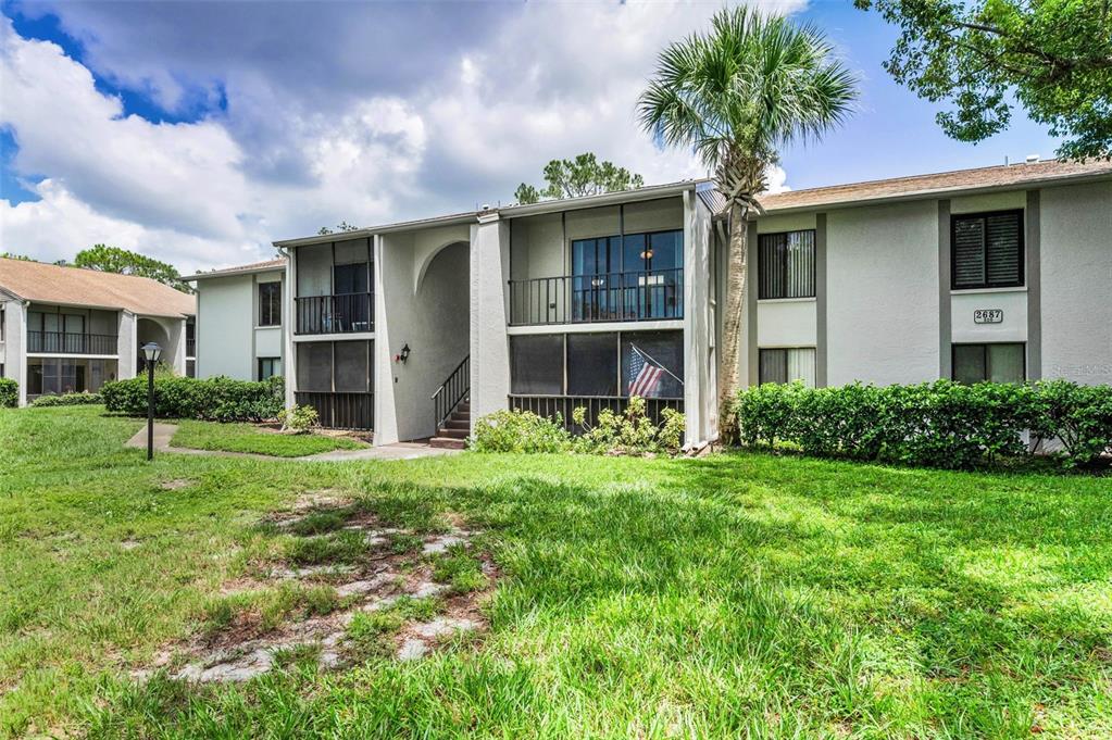 2687 Pine Ridge Way South, Unit F2 Palm Harbor, FL 34684 - Photo 6 of 62 a front view of a house with a yard and potted plants
