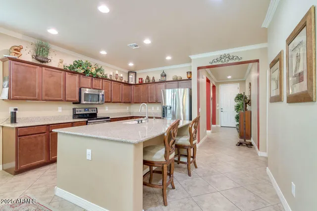 a kitchen with stainless steel appliances kitchen island granite countertop a table chairs sink and cabinets