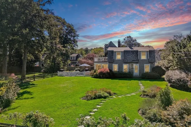 a view of a house with a big yard plants and large trees