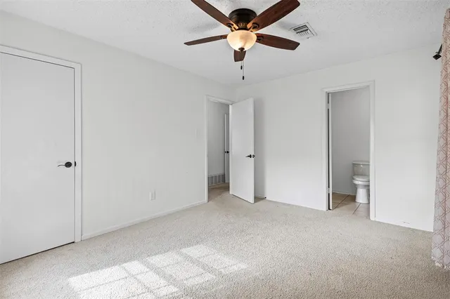 a view of an empty room and chandelier fan