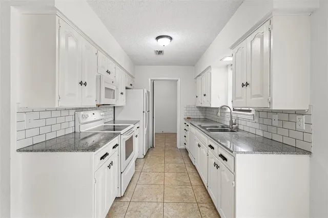 a large white kitchen with stainless steel appliances granite countertop a sink and dishwasher a stove with wooden floors