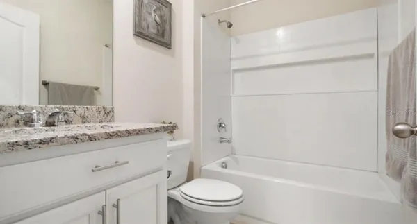 a bathroom with a granite countertop sink a toilet and shower