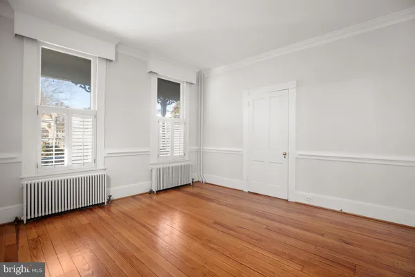 an empty room with wooden floor and windows