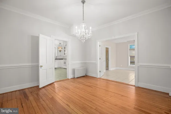 a view of empty room with wooden floor and kitchen view