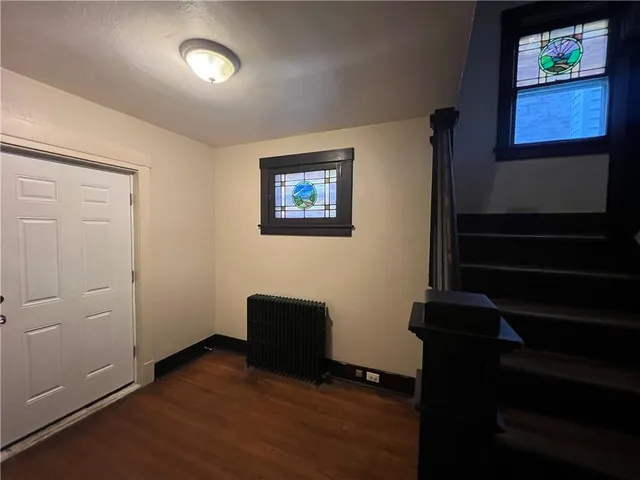 a view of an empty room with wooden floor and windows