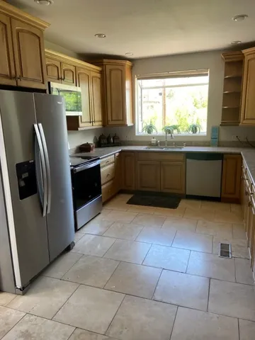 a white kitchen with stainless steel appliances granite countertop a refrigerator sink and microwave