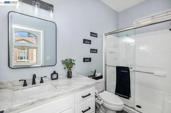 a bathroom with a granite countertop sink mirror vanity and toilet