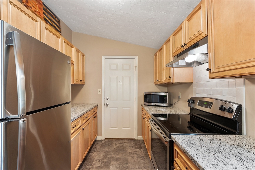 425 Main Street, Unit 8B Hudson, MA 01749 - Photo 11 of 31 a kitchen with granite countertop a refrigerator stove and oven
