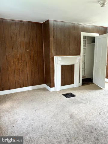 a view of an empty room with wooden floor and a fireplace